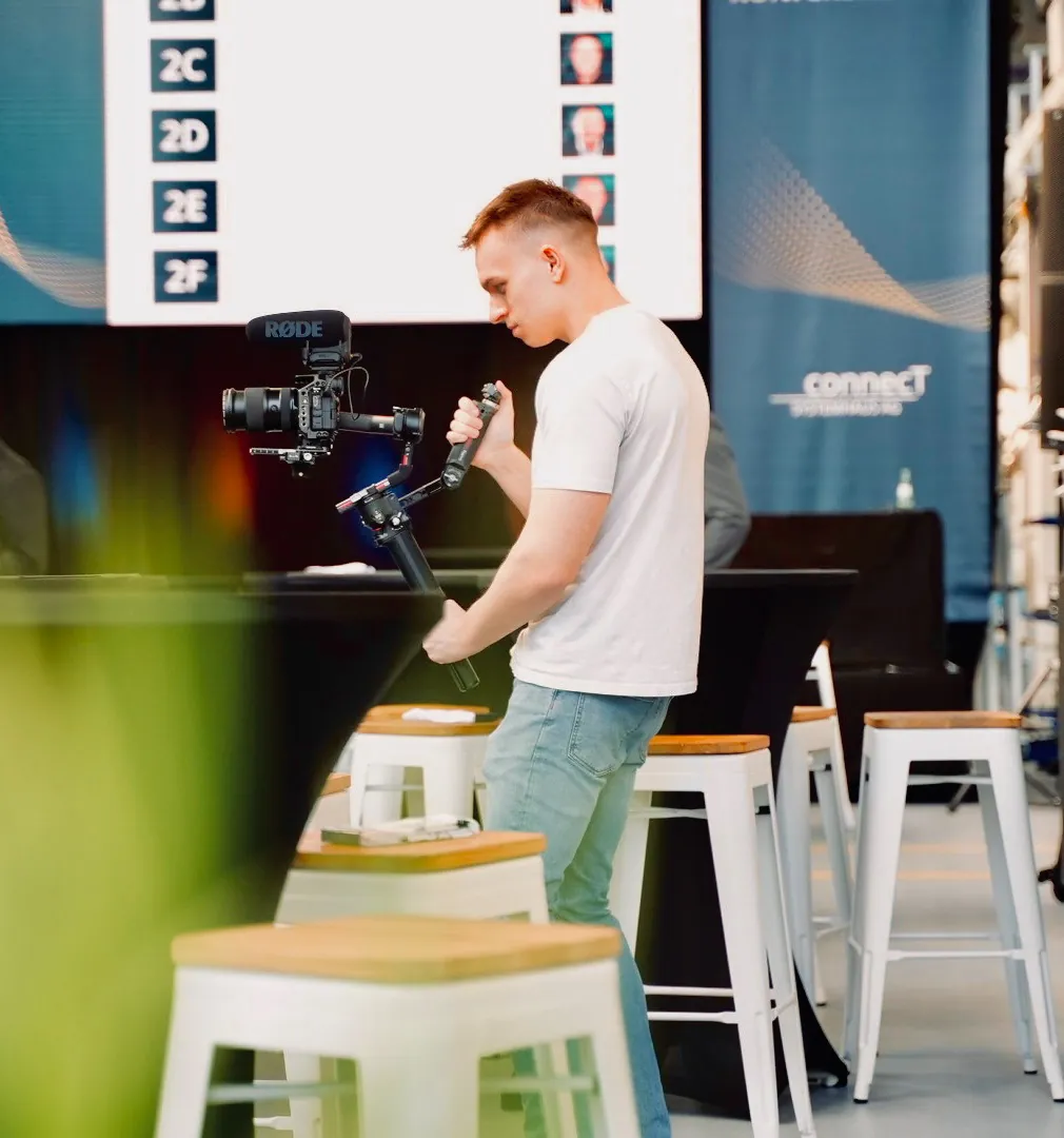 Videograf an der Kamera vor einer Bühne mit Präsentationsleinwand