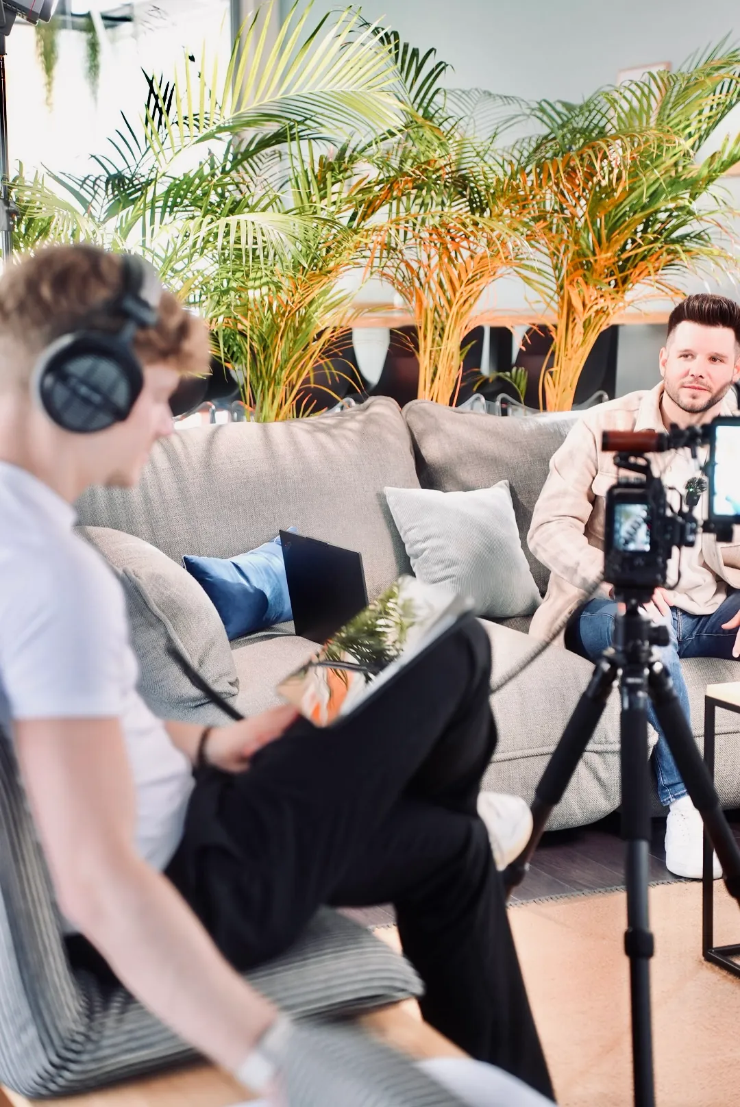 Interview auf einem Sofa, im Vordergrund das Teammitglied mit Kopfhörern