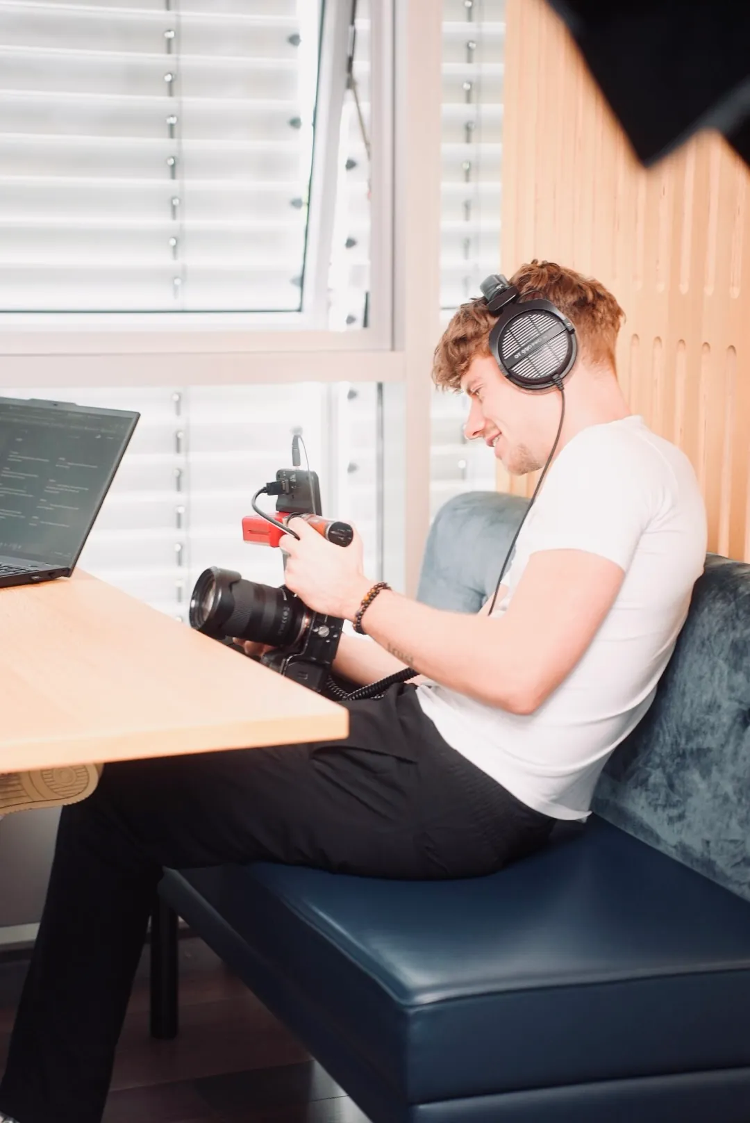 Teammitglied mit Kopfhörern und Kamera auf einem Sofa