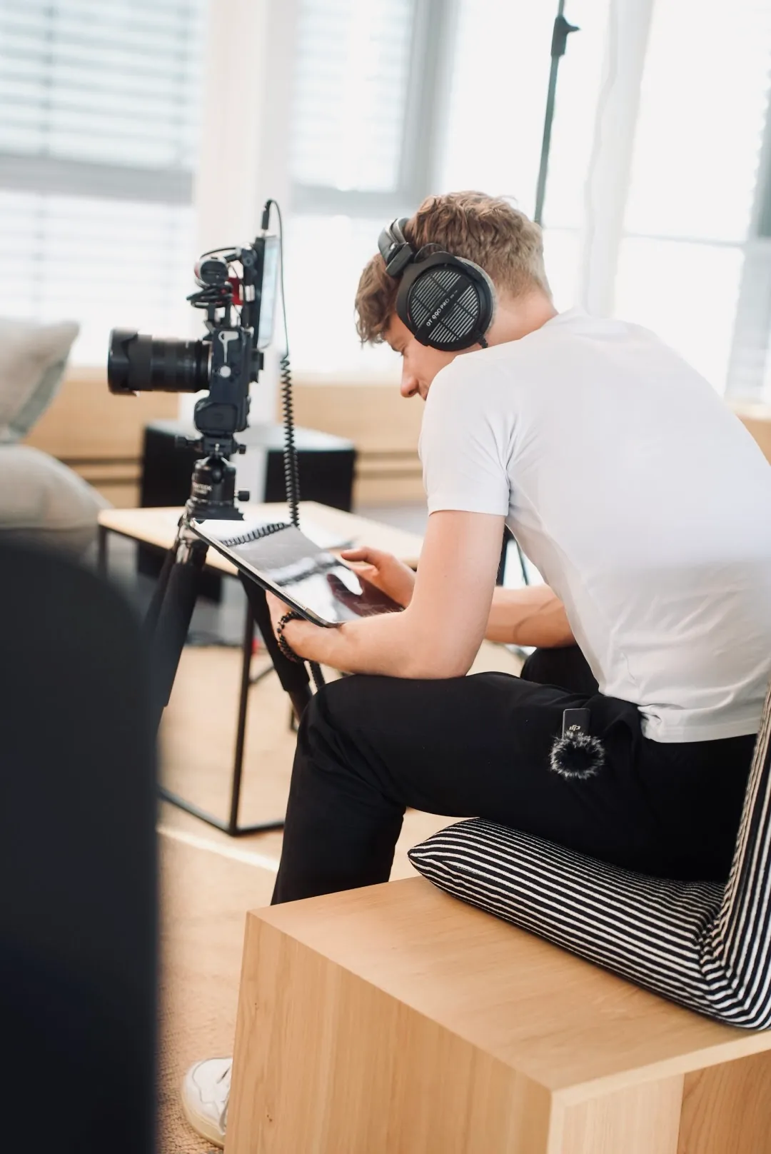 Teammitglied mit Kopfhörern prüft am Laptop die Aufnahme, daneben die Kamera auf dem Stativ